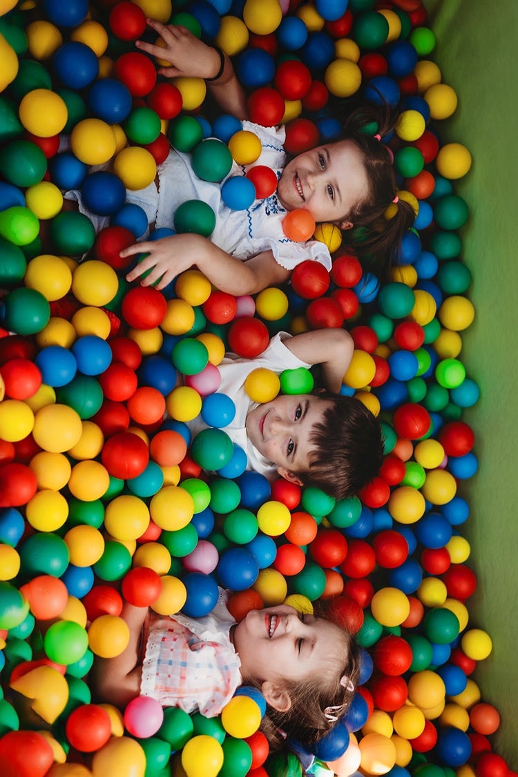 Dzieci bawią się razem w basenie wypełnionym kolorowymi piłeczkami. Taka aktywność rozwija koordynację ruchową, orientację przestrzenną i integrację sensoryczną, a jednocześnie daje dużo radości i sprzyja wspólnemu spędzaniu czasu.