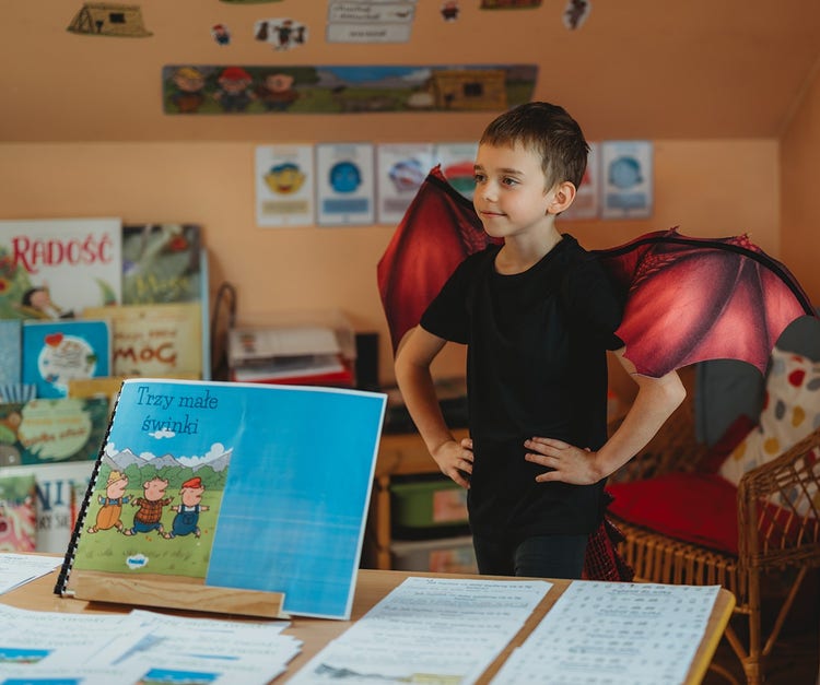Dziecko podczas zajęć edukacyjnych w Przedszkolu Scherzo w Krakowie, uczestniczące w pracy z książką i odgrywaniu ról rozwijając wyobraźnię i pewność siebie
